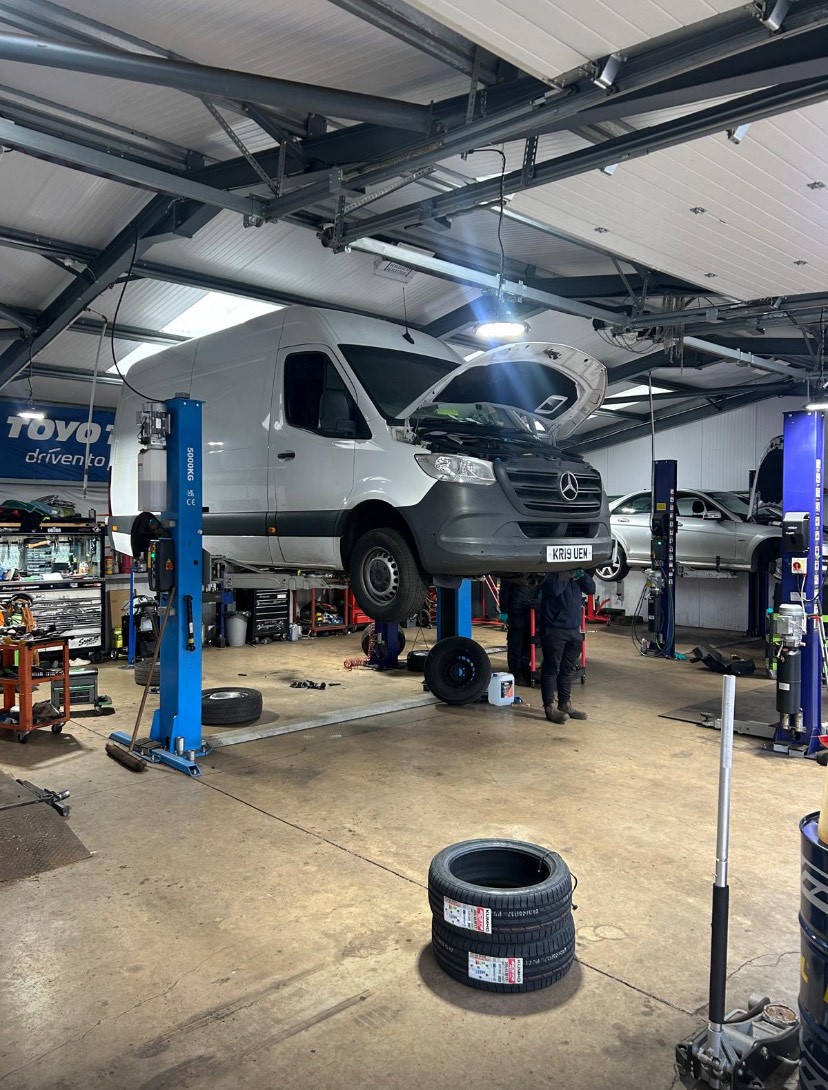 Inside the Finlayson Autos workshop: a van raised on a two-post lift with a mechanic working underneath